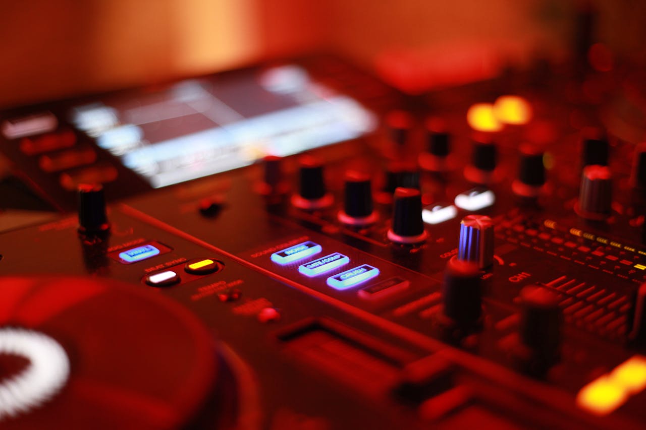 Vibrant close-up of an illuminated DJ mixing console showcasing knobs and controls in a dimly lit environment.