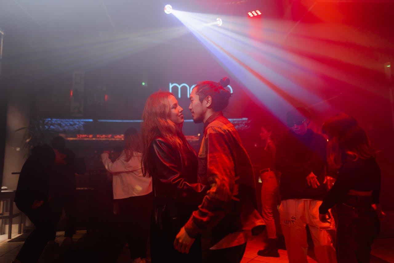 Energetic nightclub scene with couples dancing under vibrant lights.