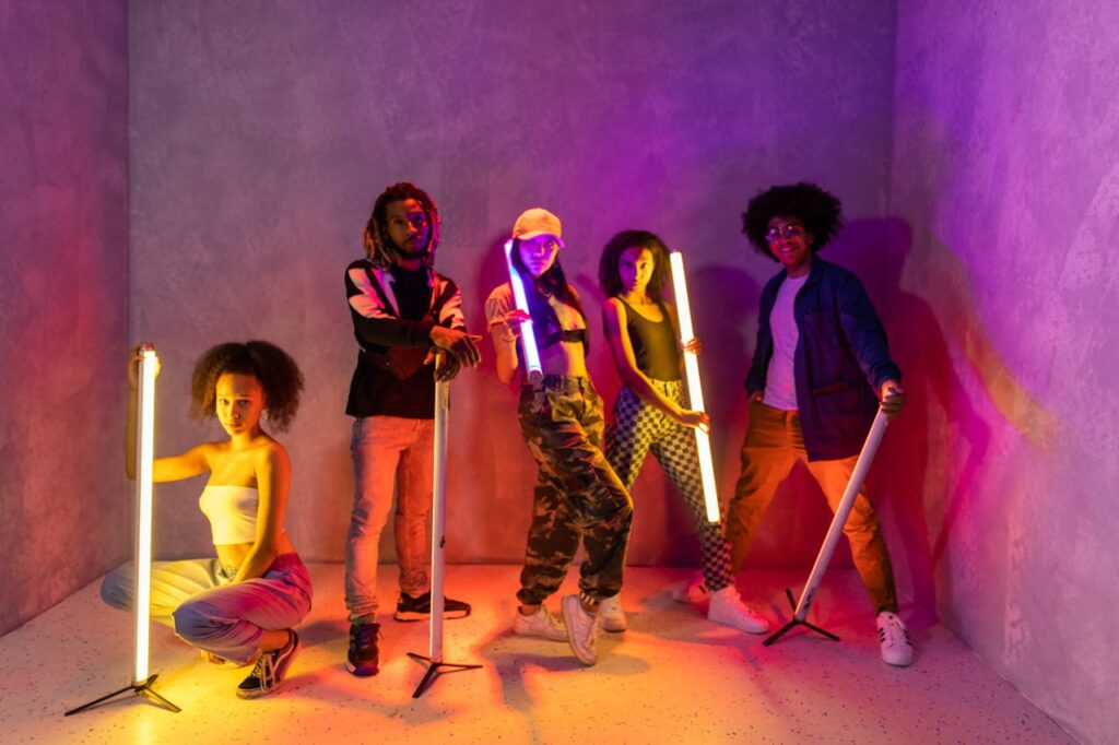 Stylish group of young adults posing with neon lights in an artistic setting.