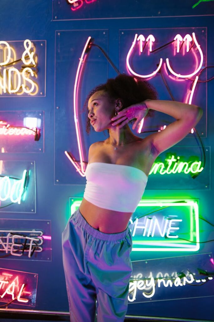 Fashionable young woman dancing in front of vibrant neon lights at a nightclub.